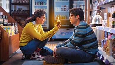 Young woman and man sitting on the floor in a store, sharing a moment of connection.