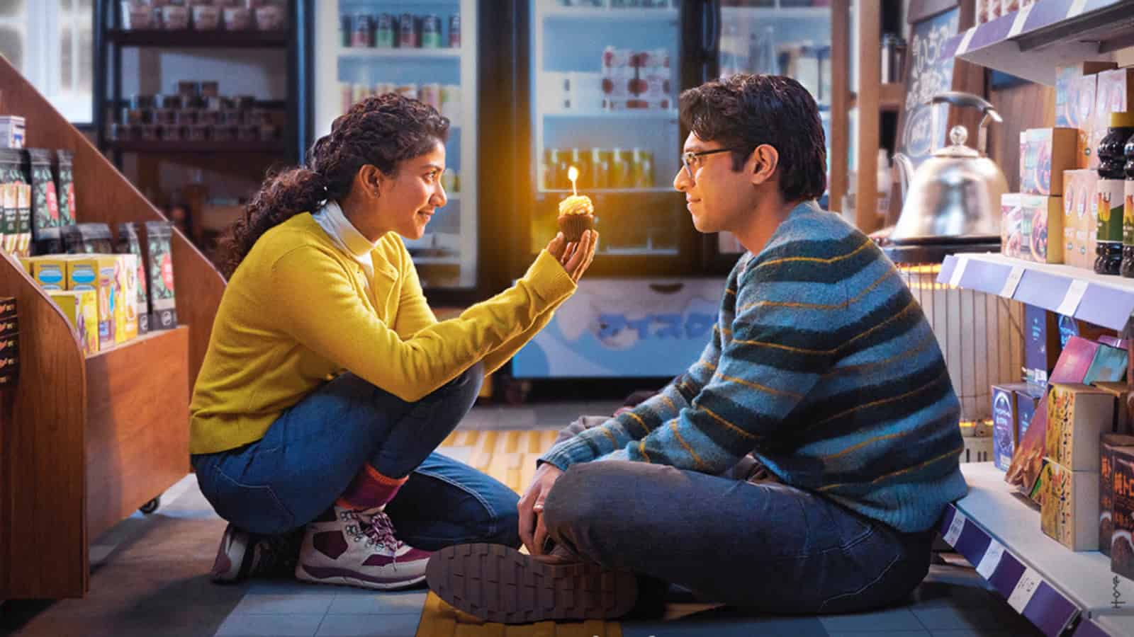 Young woman and man sitting on the floor in a store, sharing a moment of connection.