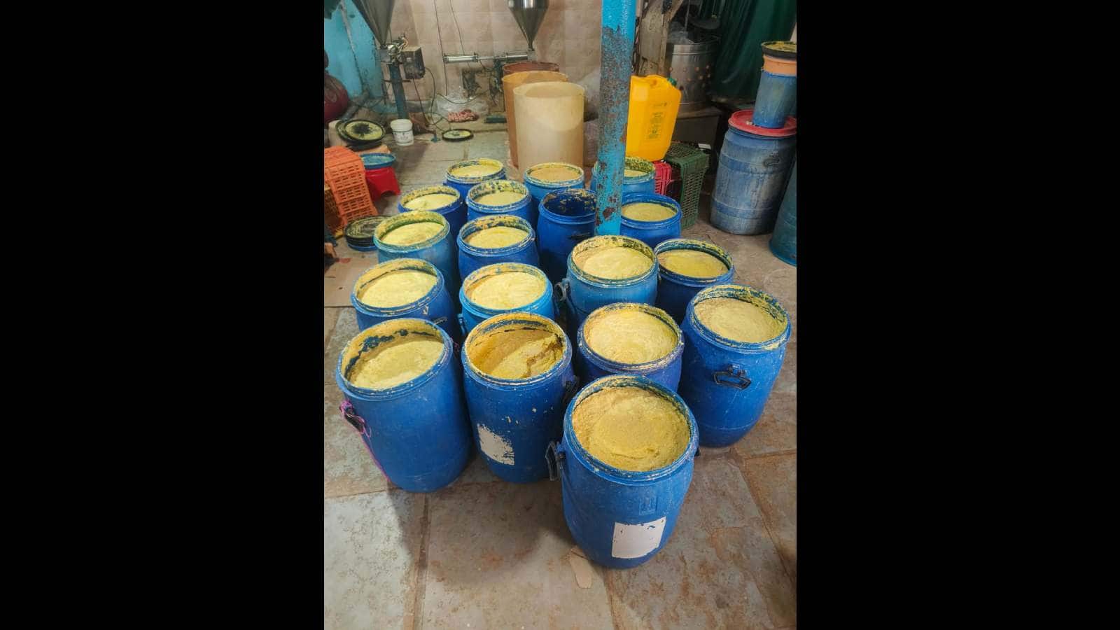 Blue barrels filled with seized adulterated ginger garlic paste in a storage area.