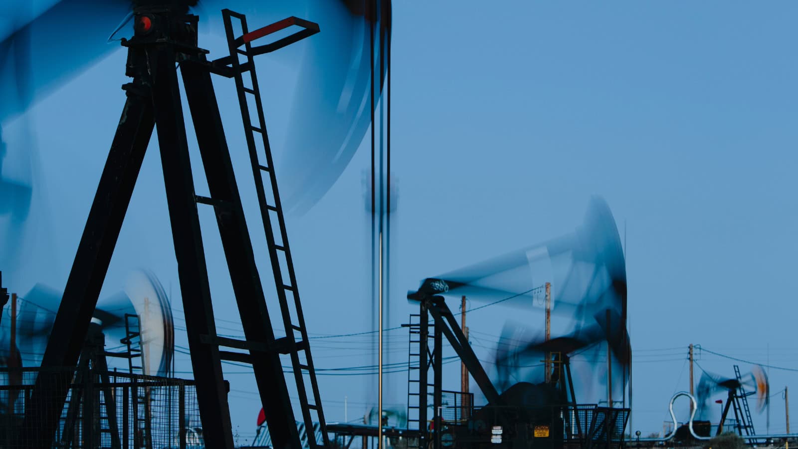 Oil pump jacks at work in an oilfield during daytime.
