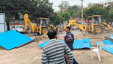 Workers and machinery demolish blue fencing on government land in Attapur.