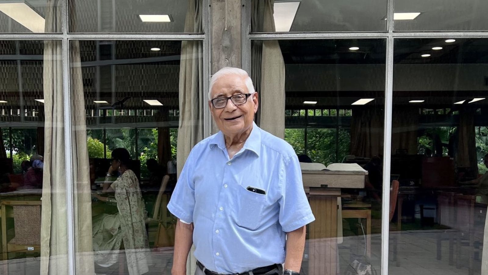 HK Dua, renowned journalist and diplomat, smiling in a light blue shirt at a public event.