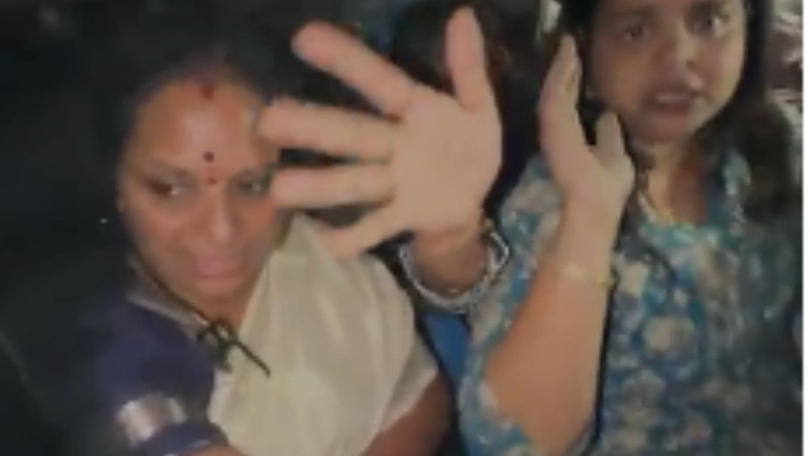 Kavitha protesting with a raised hand and a phone, expressing opposition to construction activities on th.