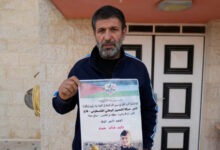 Khalid Ahmad holds a poster of his 17-year-old son, Walid Ahmad, who died in an Israeli prison, that read in Arabic, The hero prisoner Martyr, mercy and eternity for our righteous Martyrs.