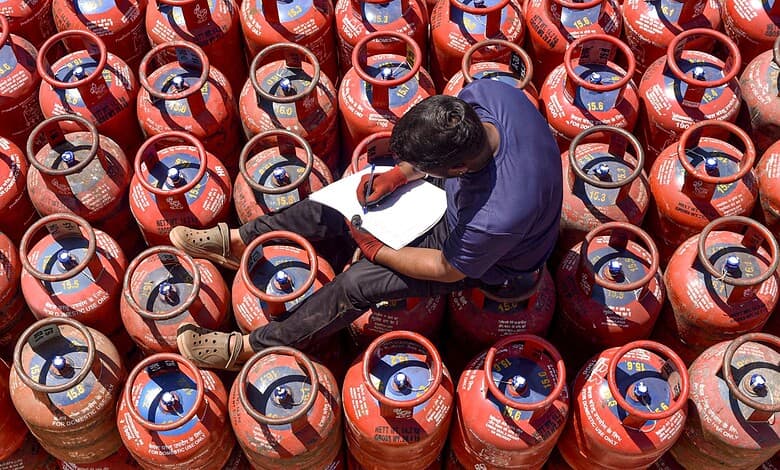 A worker sits over LPG cylinders during distribution at a gas agency.