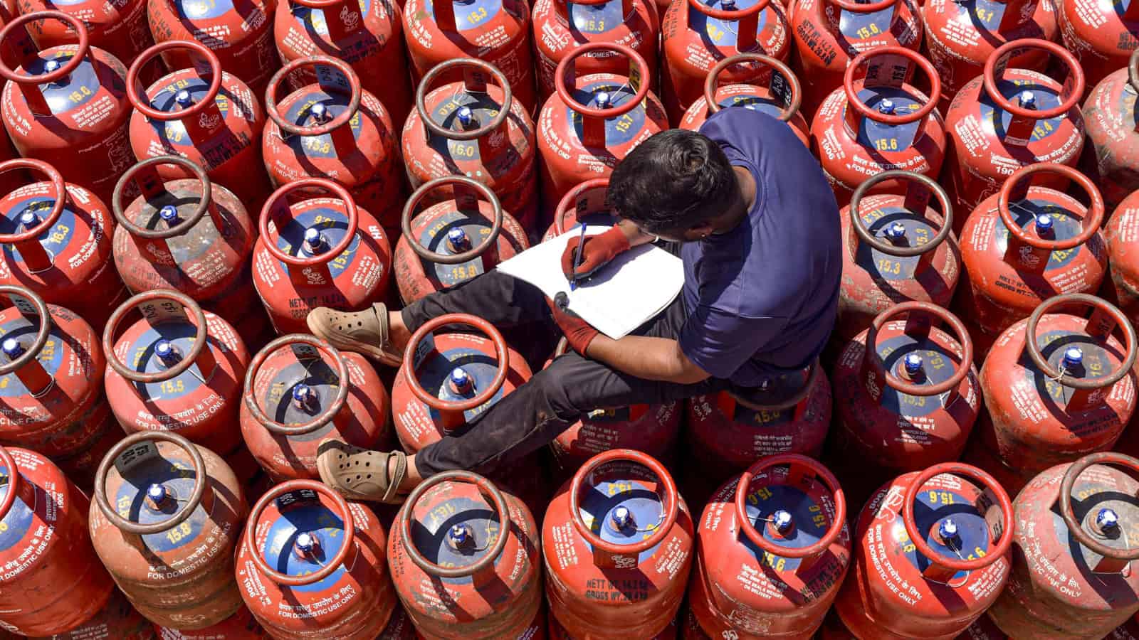 A worker sits over LPG cylinders during distribution at a gas agency.