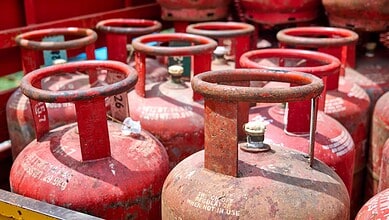 Row of red LPG cylinders stacked outdoors, ready for distribution or sale.