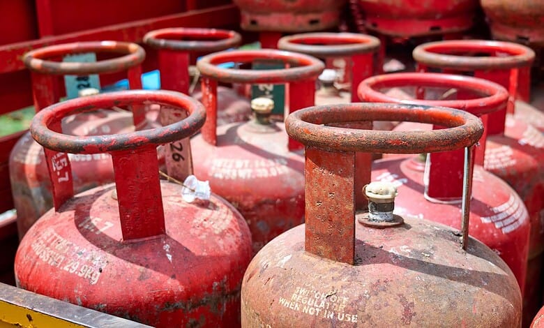 Row of red LPG cylinders stacked outdoors, ready for distribution or sale.