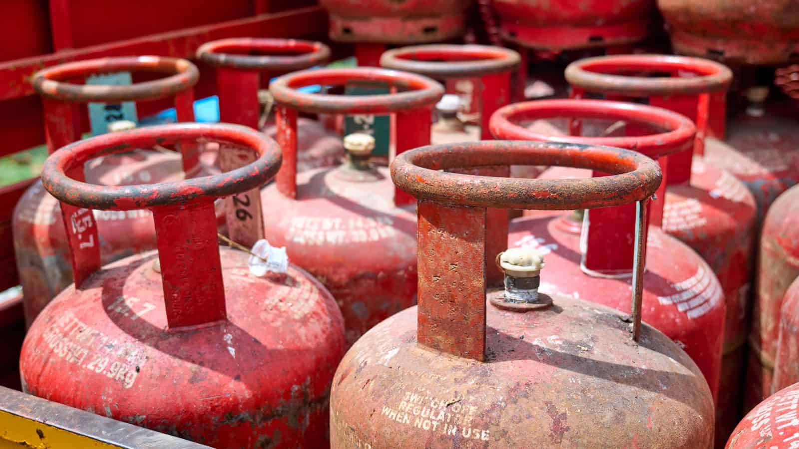 Row of red LPG cylinders stacked outdoors, ready for distribution or sale.