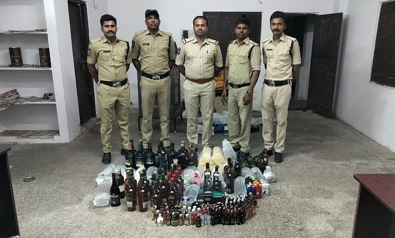 Police officers with seized bottles of alcohol in a room.