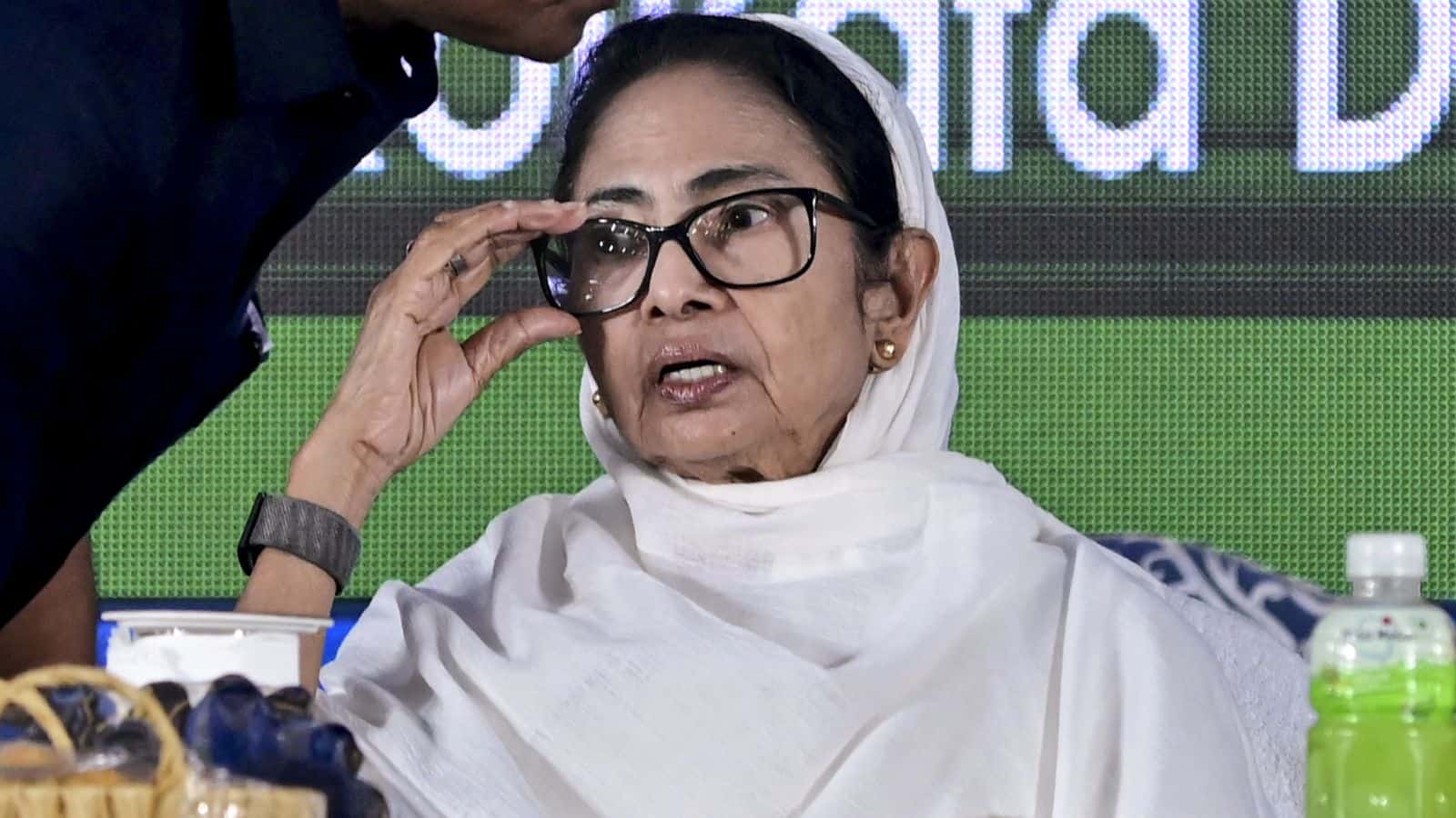 Mamata Banerjee adjusting her glasses at a political event, highlighting her active engagement in regiona.