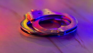 Handcuffs on a wooden surface, representing legal action against public nuisance offences.