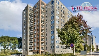 Modern multi-storey residential building with trees and clear sky in the background.