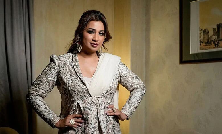 Shreya Ghoshal posing confidently at an event, wearing a silver embroidered outfit.