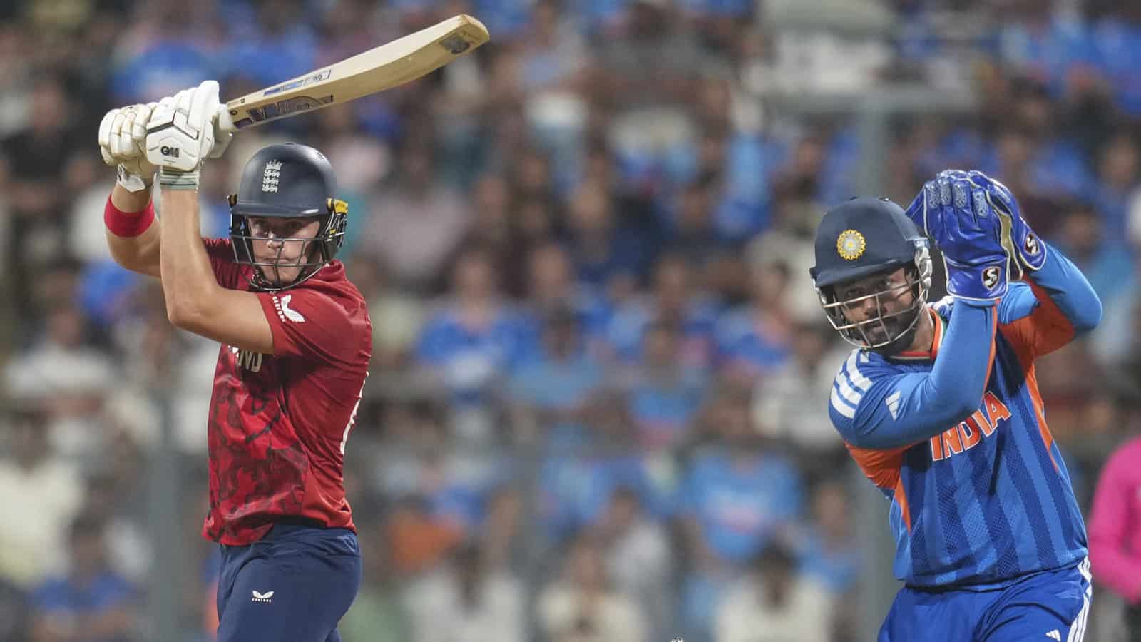 Indian and English cricket players competing in a match with a crowd in the background.
