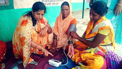 Women receiving blood pressure measurement at a health camp.