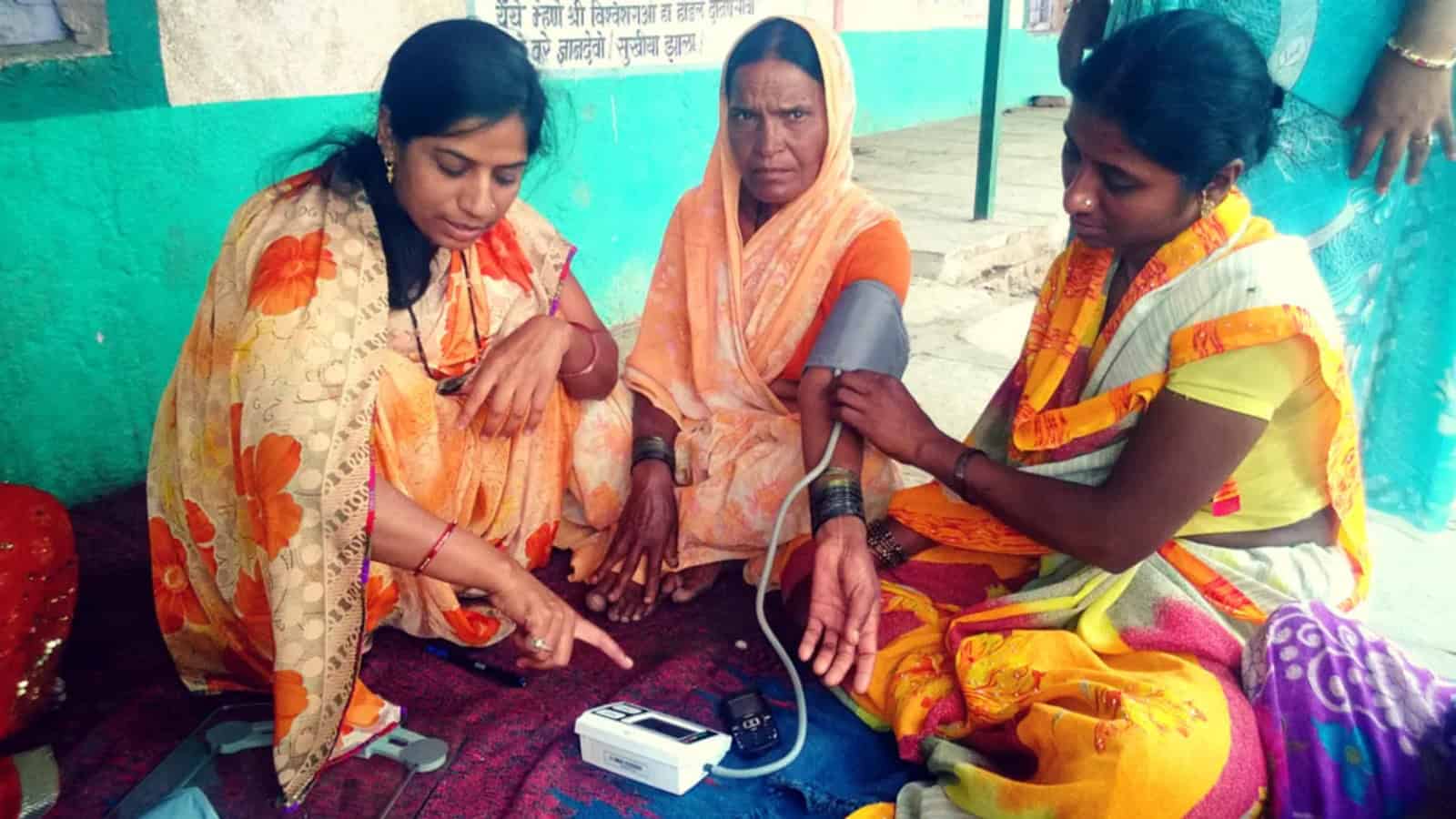 Women receiving blood pressure measurement at a health camp.