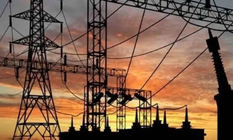 High-voltage power lines and pylons against a sunset sky in Telangana.