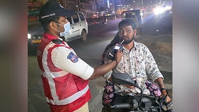 Police officer checks a motorcyclist for drunk driving during night patrol in Cyberabad.