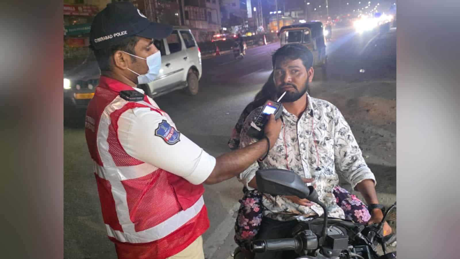 Police officer checks a motorcyclist for drunk driving during night patrol in Cyberabad.