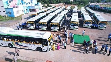 Buses at Telangana bus station, with passengers boarding and alighting, under clear weather.