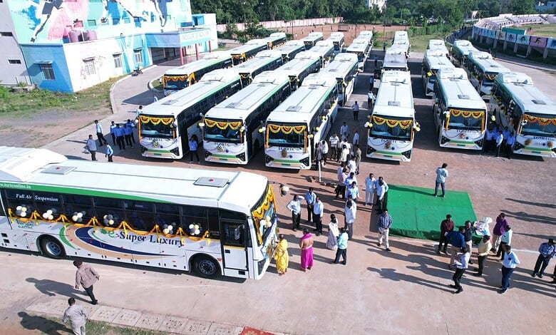 Buses at Telangana bus station, with passengers boarding and alighting, under clear weather.