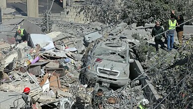 An image showing the aftermath of a military attack with damaged vehicles, rescue workers, and debris, hi.