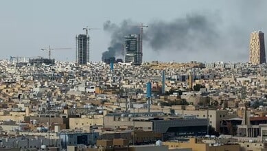 Explosion and smoke over a city skyline with ongoing construction and urban development.
