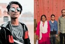 Young man with sunglasses and casual attire standing outdoors, with a group of people in the background.
