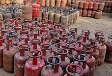 Large collection of red LPG cylinders stored outdoors in a yard.