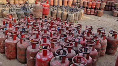 Large collection of red LPG cylinders stored outdoors in a yard.