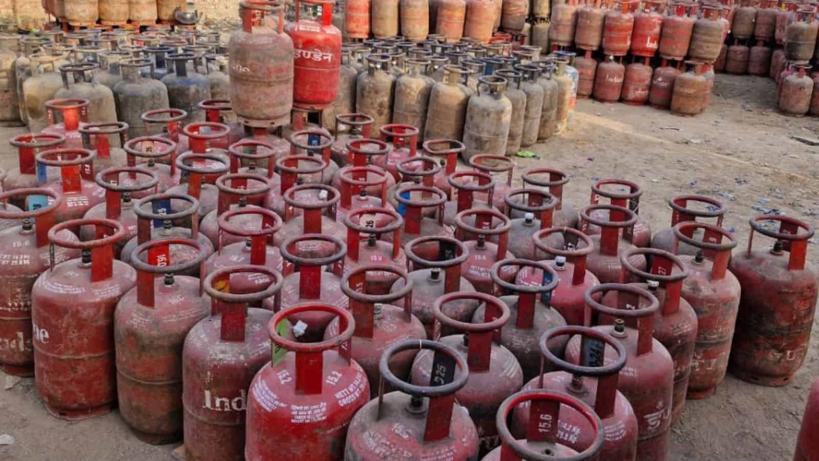 Large collection of red LPG cylinders stored outdoors in a yard.