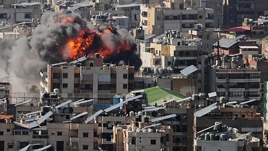Explosion in Tehran cityscape with smoke and fire amid urban buildings.