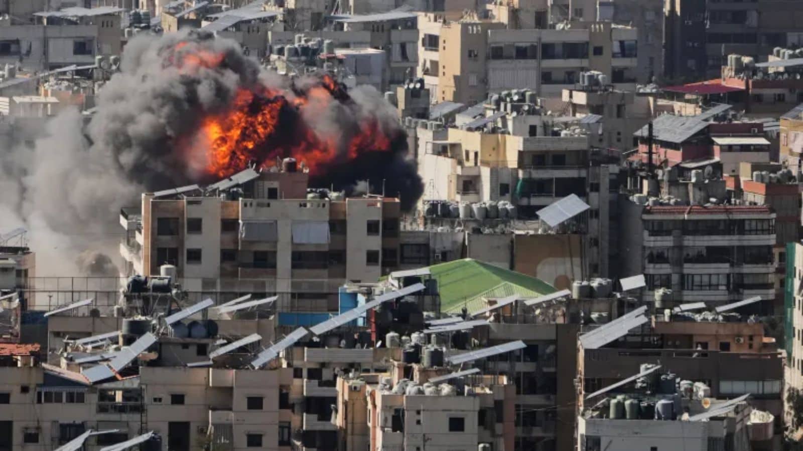 Explosion in Tehran cityscape with smoke and fire amid urban buildings.
