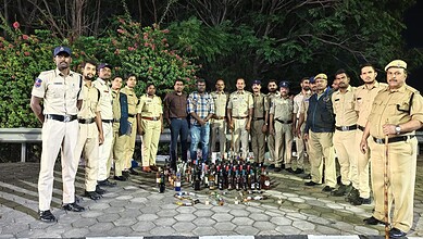Telangana excise officials with seized liquor bottles