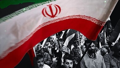 Iranian protesters waving flags in a defiant rally against US and Israel.