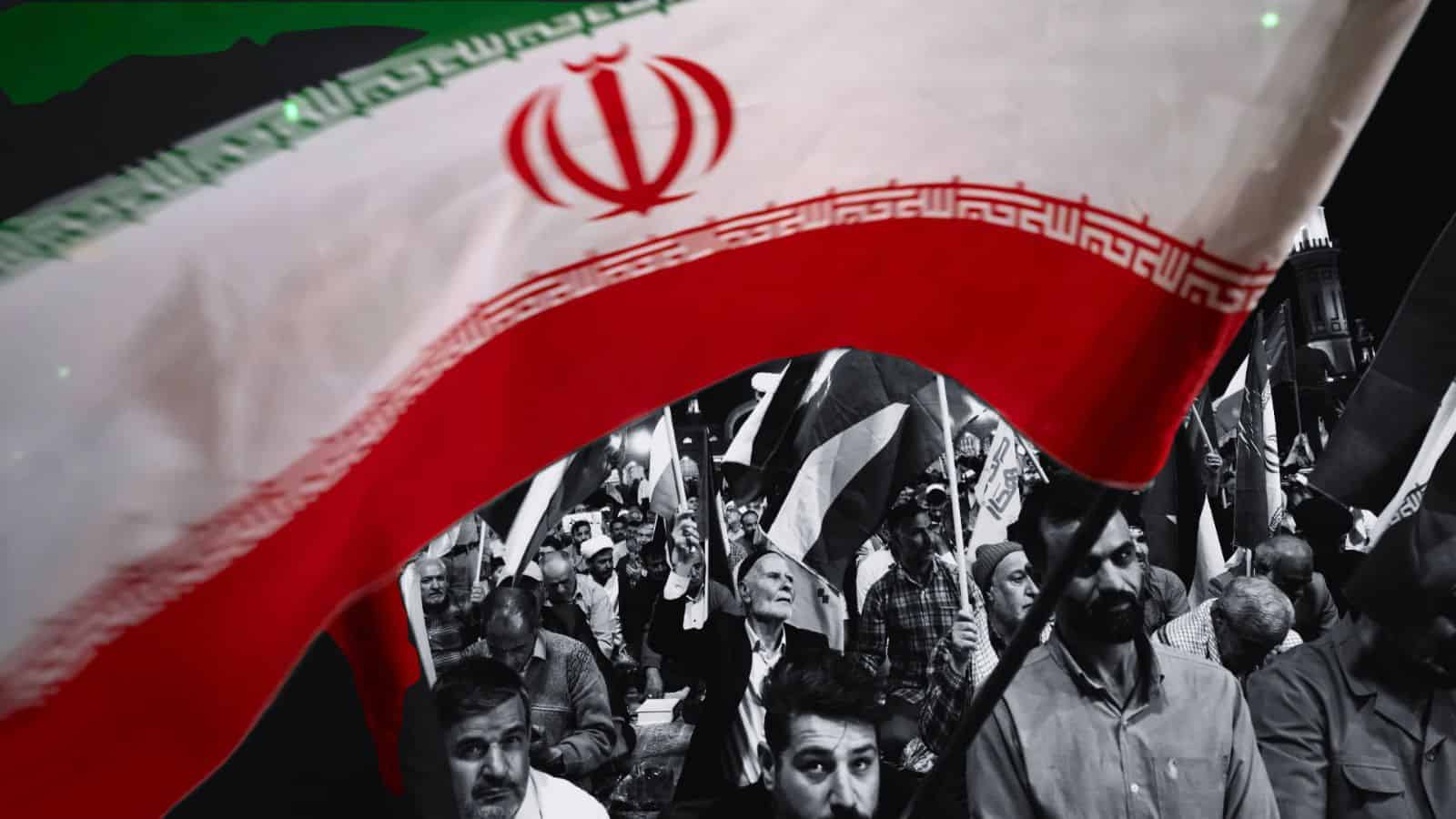 Iranian protesters waving flags in a defiant rally against US and Israel.