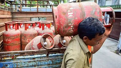 Gas cylinders stacked outdoors, man inspecting for safety or maintenance.
