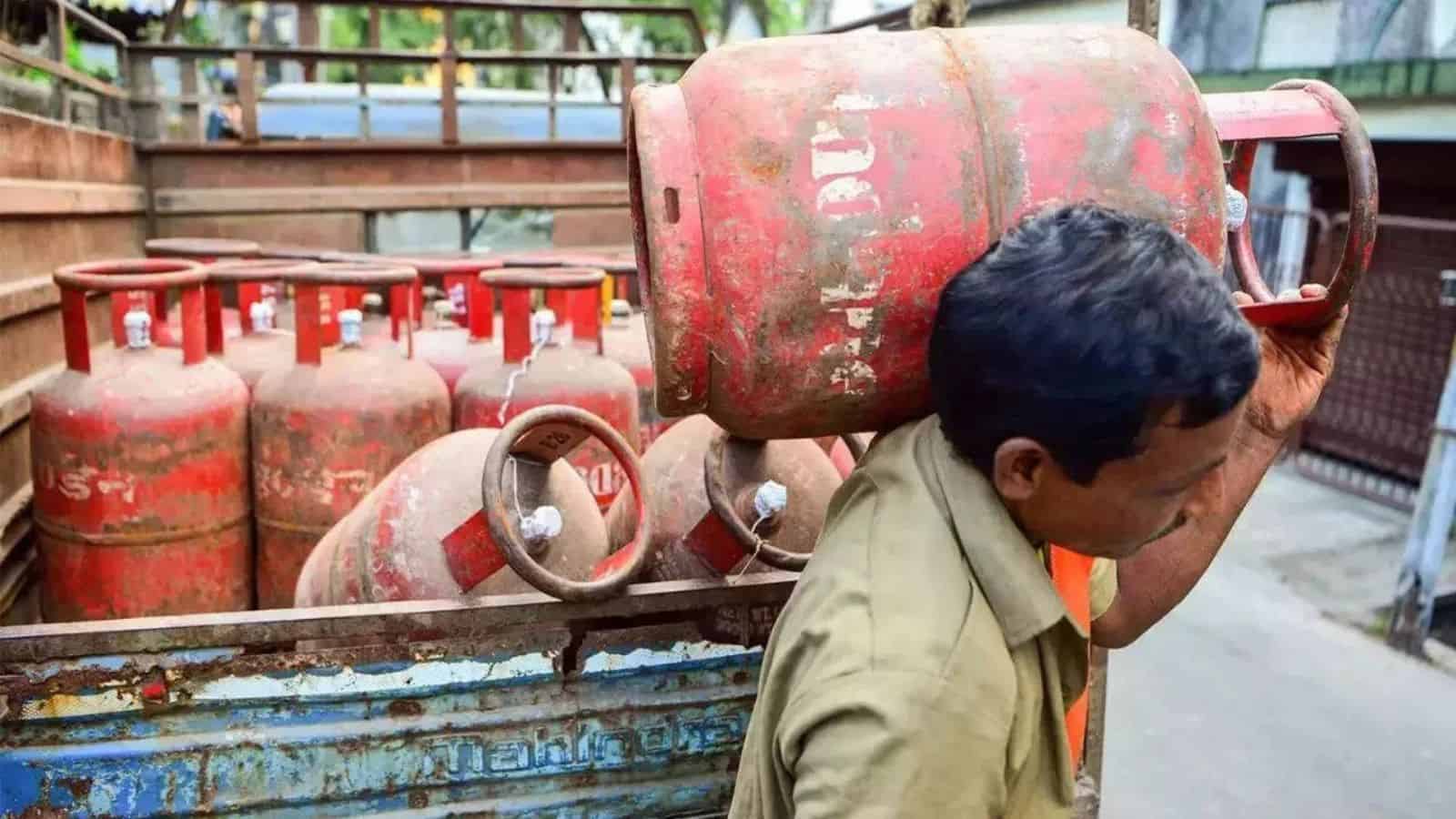 Gas cylinders stacked outdoors, man inspecting for safety or maintenance.