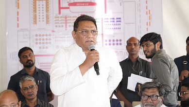 A political leader addressing the media during a press conference with journalists and staff present.
