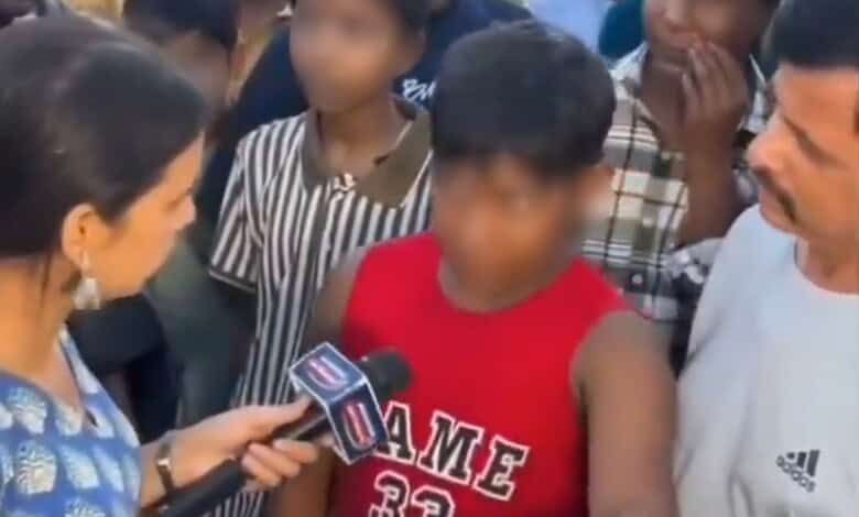 Young boy in red shirt speaking passionately to media surrounded by adults and children.