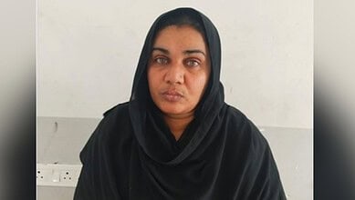 A confident woman wearing a black hijab, looking directly at the camera with a serious expression.