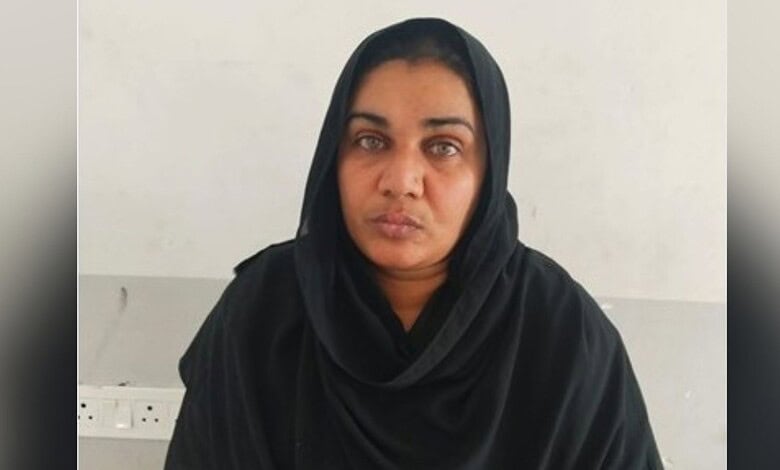 A confident woman wearing a black hijab, looking directly at the camera with a serious expression.