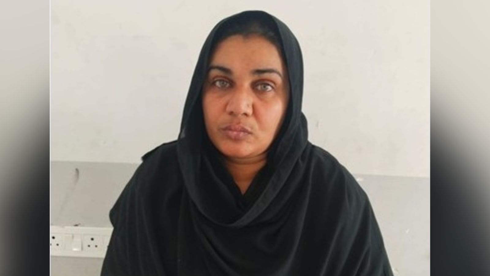 A confident woman wearing a black hijab, looking directly at the camera with a serious expression.