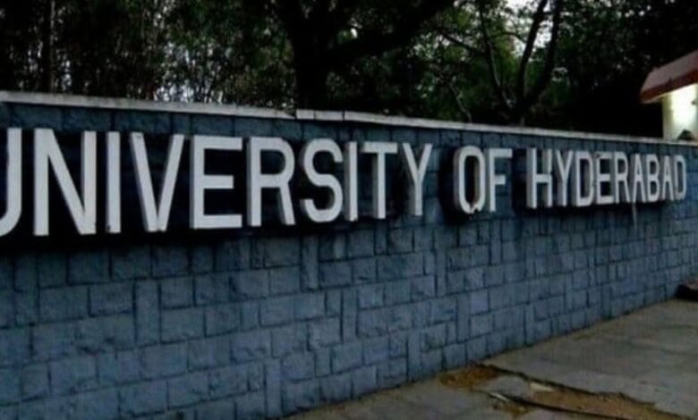 University of Hyderabad signboard with campus trees in background.
