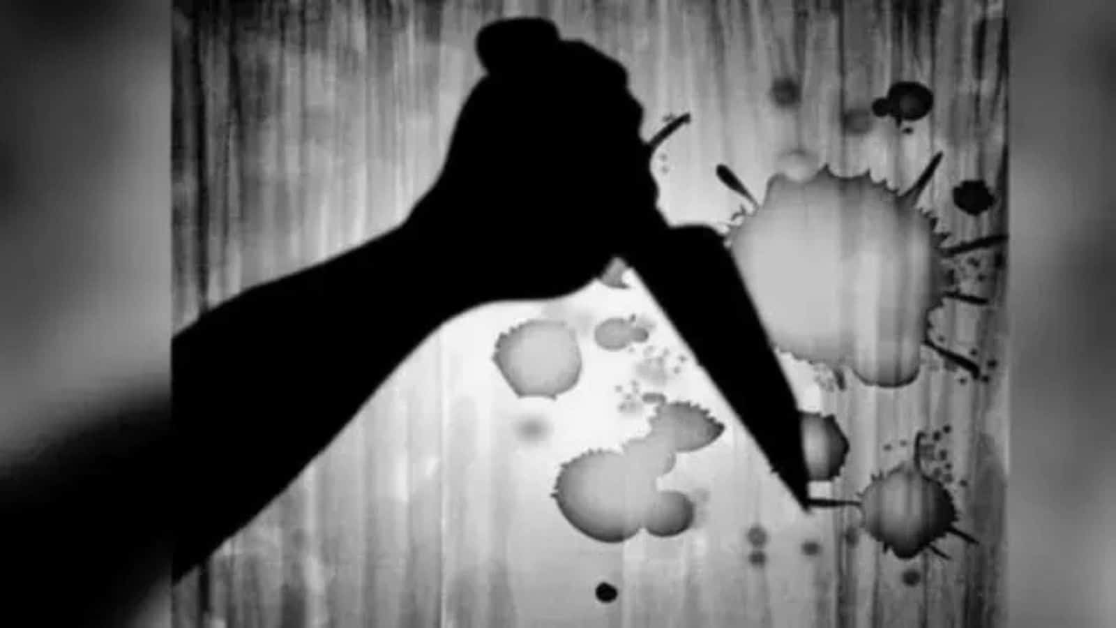 Silhouette of a hand holding a knife with ink splatters on a wooden background.