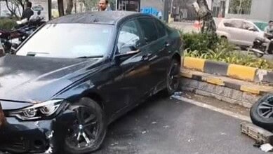 Black BMW sedan involved in a collision with the median on a city street in Hyderabad.