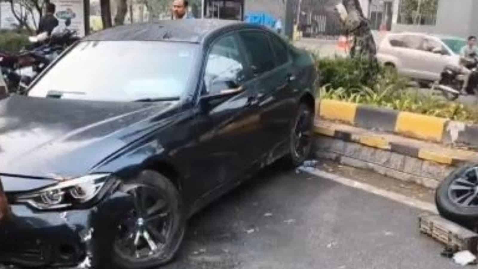 Black BMW sedan involved in a collision with the median on a city street in Hyderabad.