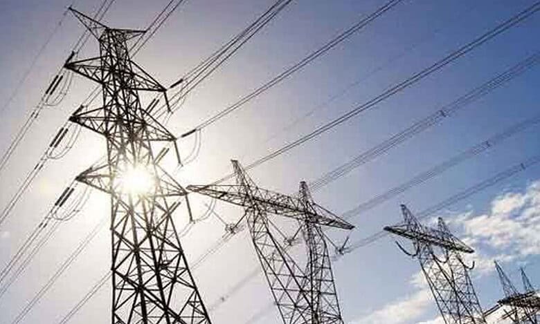 High-voltage power lines on transmission towers against a sunny sky.