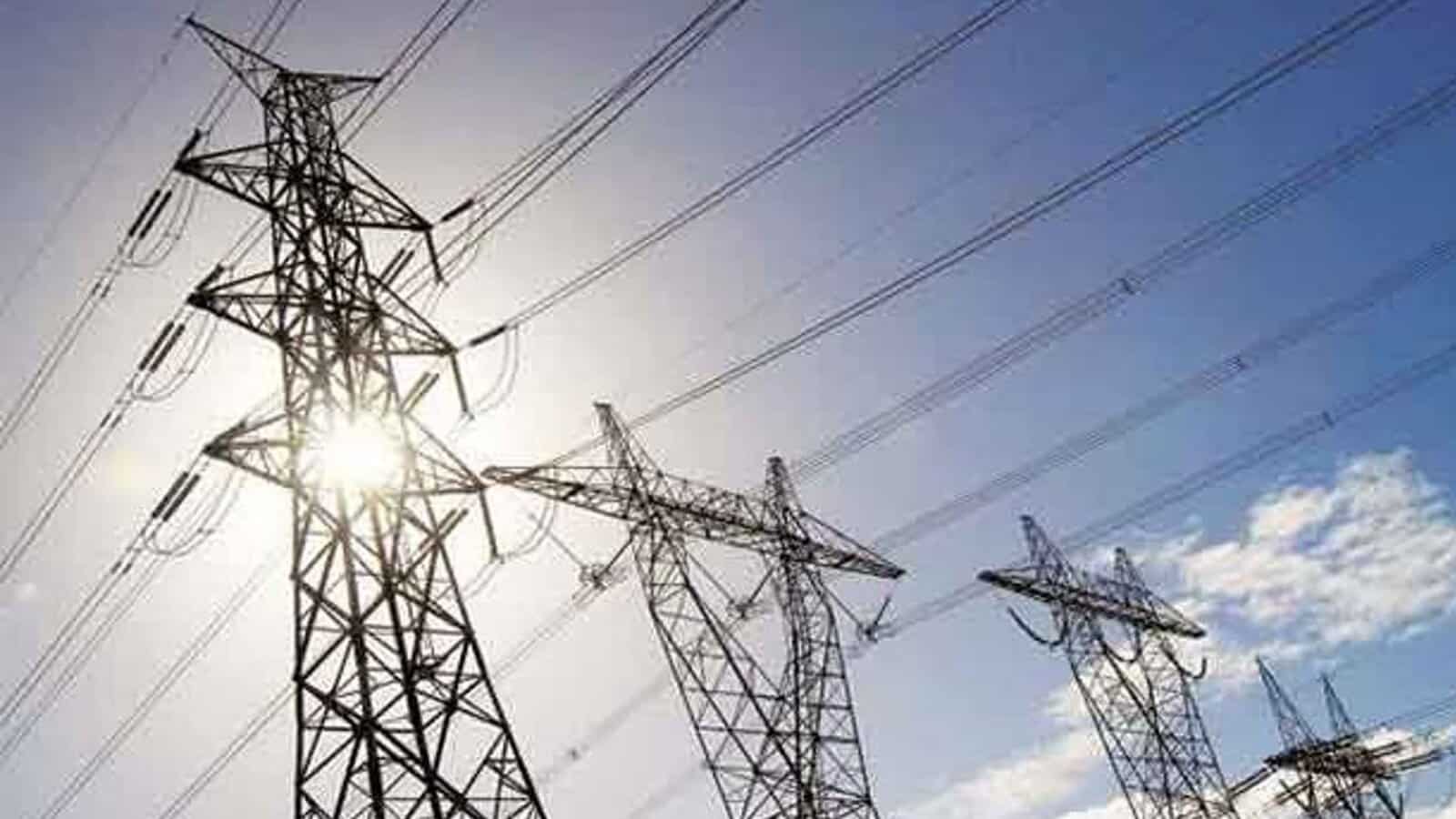 High-voltage power lines on transmission towers against a sunny sky.
